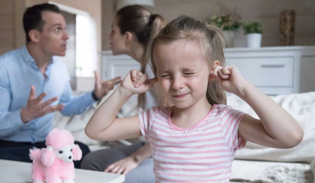 child plugging ears while parents fight